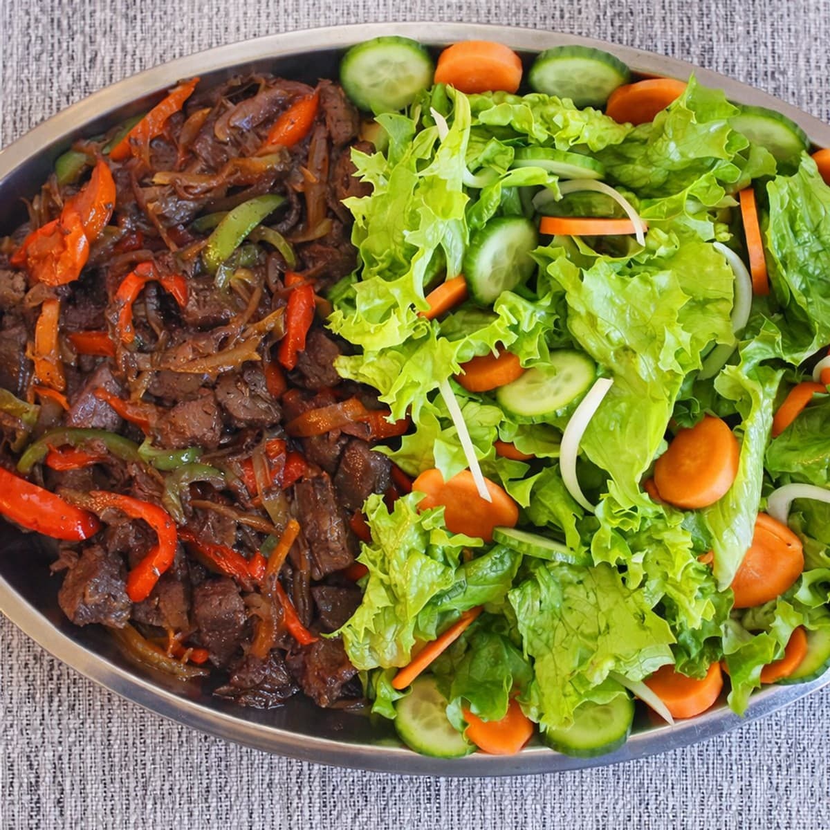 Foie d’agneau sauté aux poivrons et aux oignons accompagné de salade, carottes, concombre
