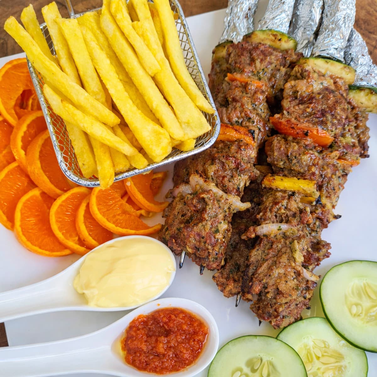 Brochettes de bœuf accompagné de salade et frites.
