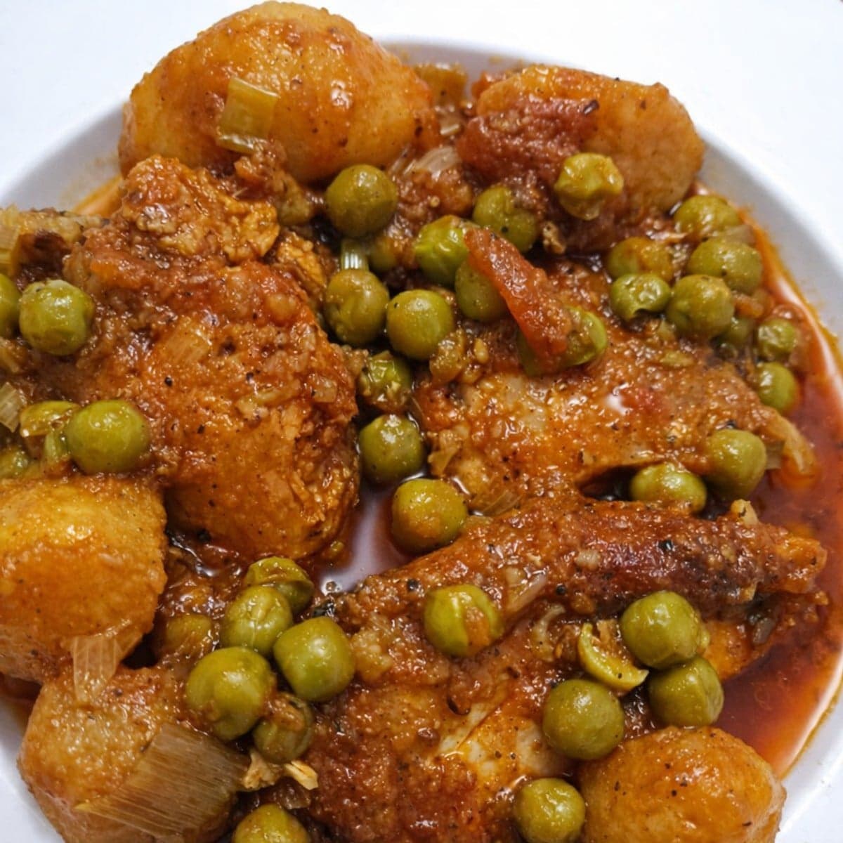 Poulet à la sauce tomate avec des petits pois et des pommes de terre.